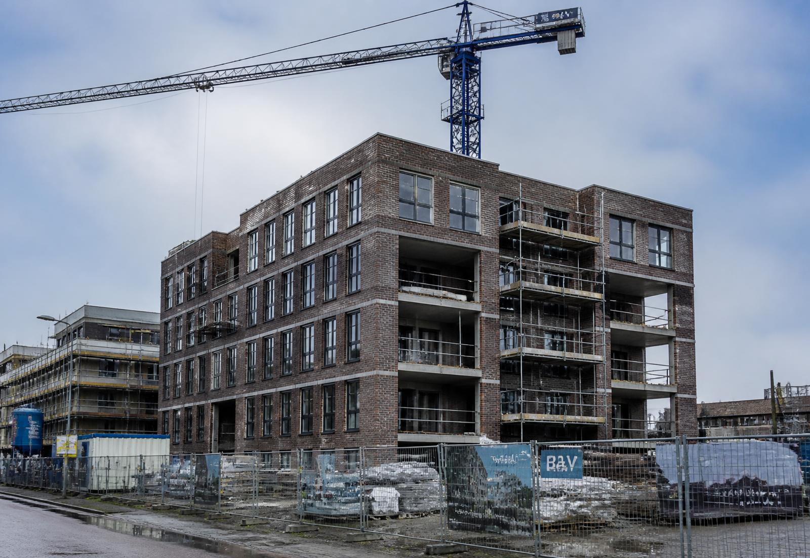 Nederlands nieuwbouwproject met bakstenen appartementengebouw, steigers en bouwkraan